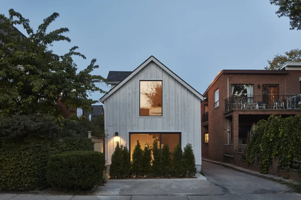 Two-storey laneway suite with vertical siding and large windows facing a rear lane